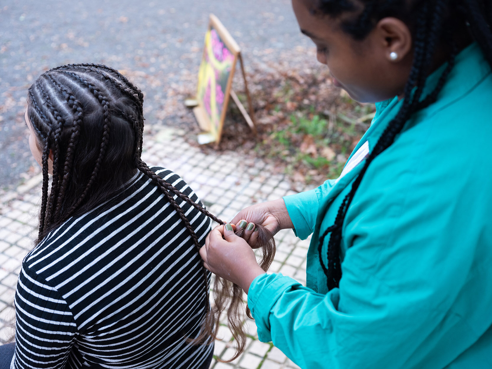 Eine Frau bekommt vor dem Salon die Haare geflochten