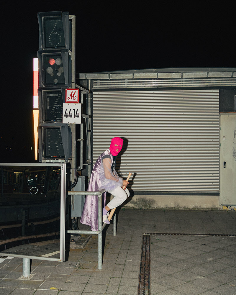 Eine Person mit Wrestlingmaske sitzt an einer Bahnstation