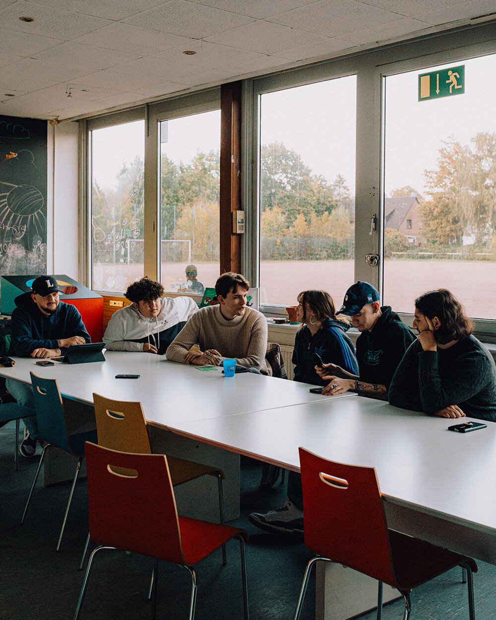 Sechs Leute sitzen beim Rap-Workshop an Schultischen