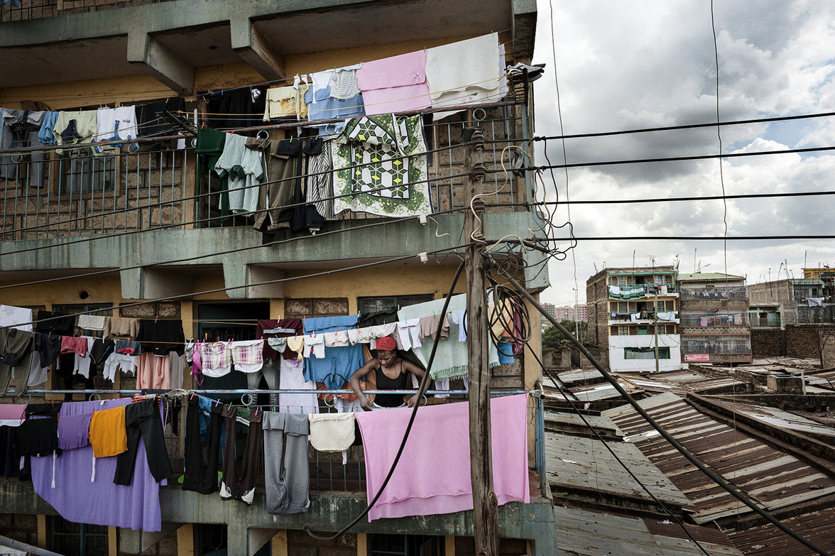 Frau hängt Wäsche auf mit Blick auf eng gebaute Wohnungen