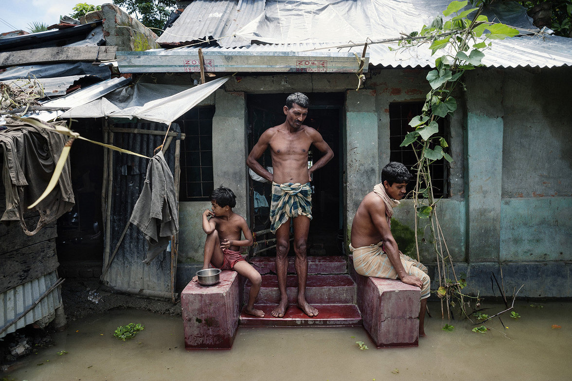 Familie vor ihrem Haus dessen Eingang überschwemmt ist