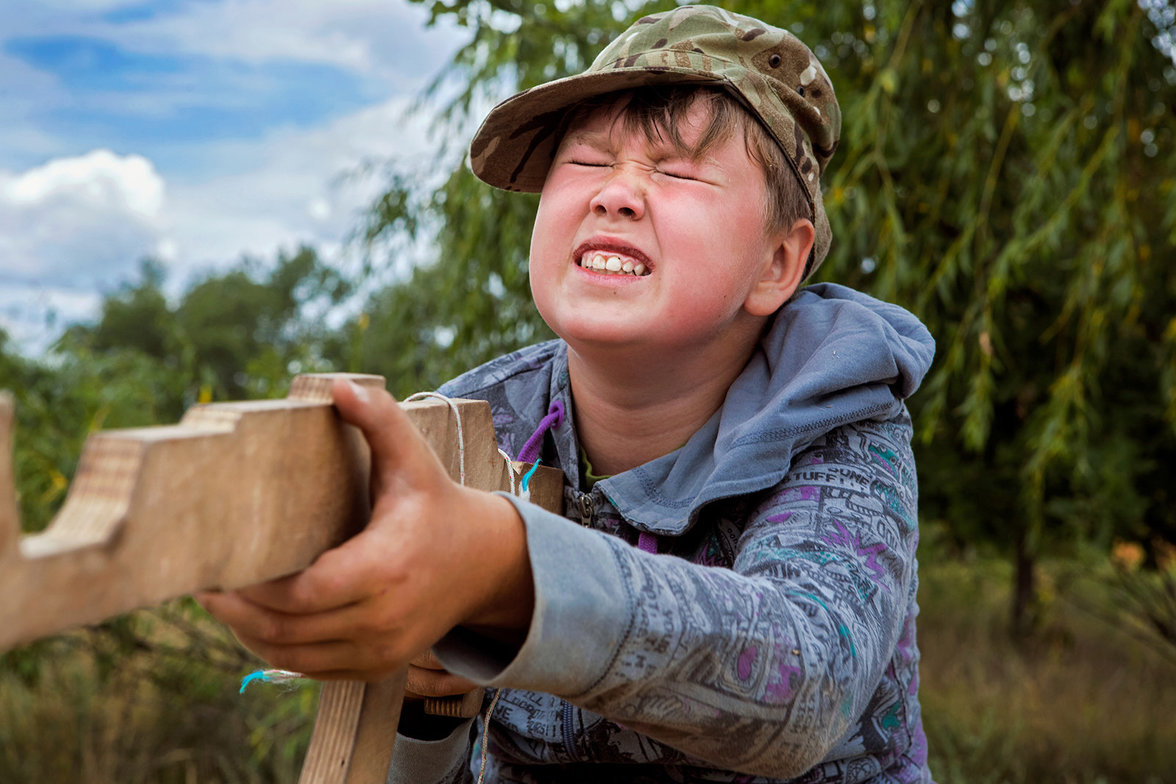 Ein Kind zielt mit einem Holzgewehr