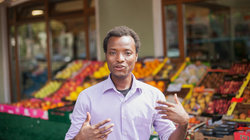 Porträt des fluter-Praktikanten Agomo Atambire aus Ghana vor einem Gemüsestand
