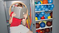 Mann in Sportkleidung hält einen Laptop, als ob er ein Buch wäre
