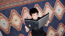 Eine Frau hält ihren Laptop wie ein Buch und liest darin