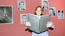 Eine jung Frauen schaut auf einen Laptop, als wäre es ein Buch