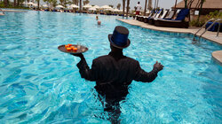 Alex aus Ghana arbeitet als "Pool Ambassador" im Ritz Carlton in Jumeirah.  Am Nachmittag serviert er Drinks am und im Pool