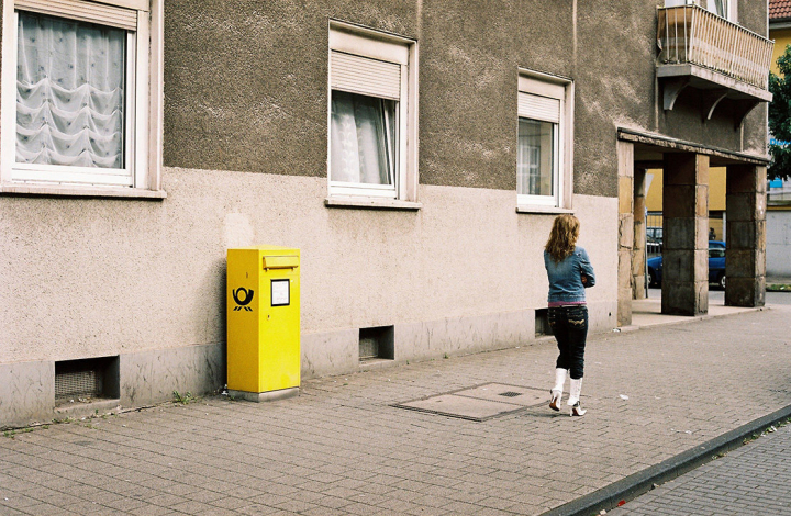 Frau läuft an einen Briefkasten vorbei