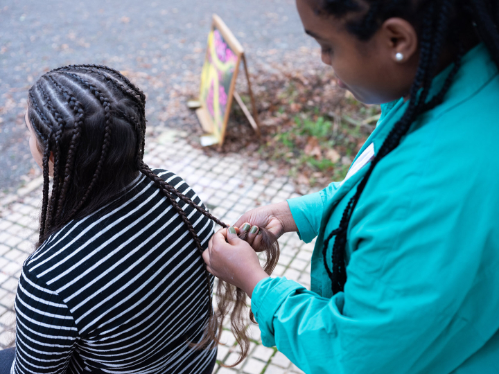 Eine Frau bekommt vor dem Salon die Haare geflochten