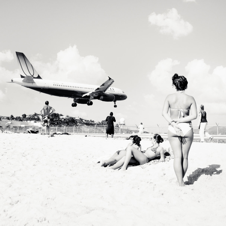 Tieffliegendes Flugzeug über Menschen am Strand 