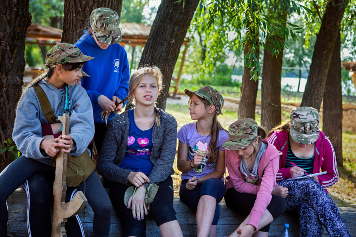 Girls participating to the ultra-nationalistic Azovets children's camp are sitting together, chatting and taking care of each other's hair, after a long day of  training on the banks of the Dnieper river, in Kiev, Ukraine's capital.