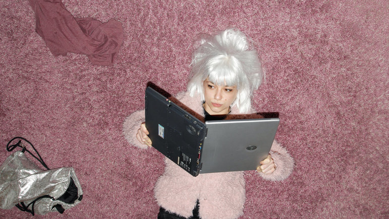 Mädchen mit Perücke liest im Laptop
