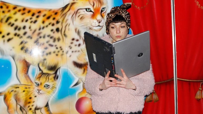 Junge Frau hält Laptop wie ein Buch und liest darin