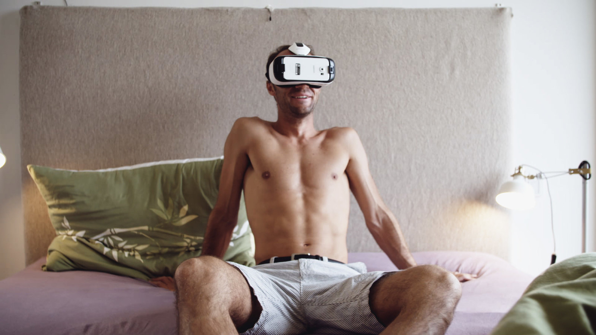 Mann mit VR Brille sitz auf dem Bett