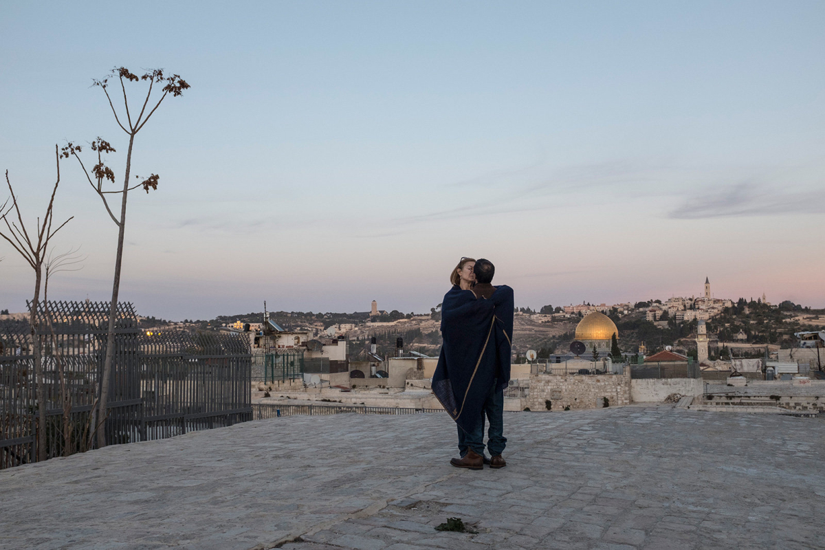 A couple has a kiss and a moment of intimacy on the rooftops.