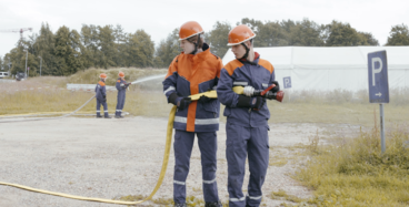 Zwei junge Freiwillige von der Feuerwehr halten einen Schlauch