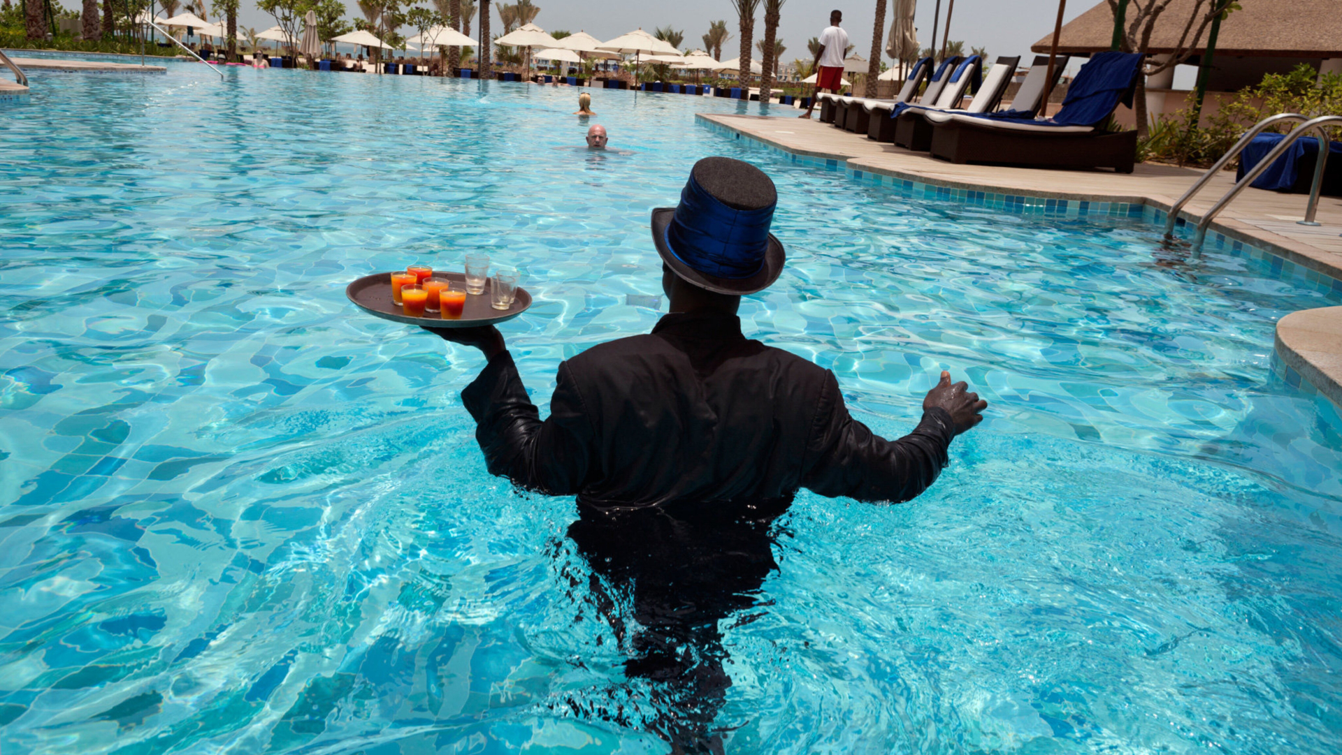 Kellner in Smoking serviert Drinks in einem Pool