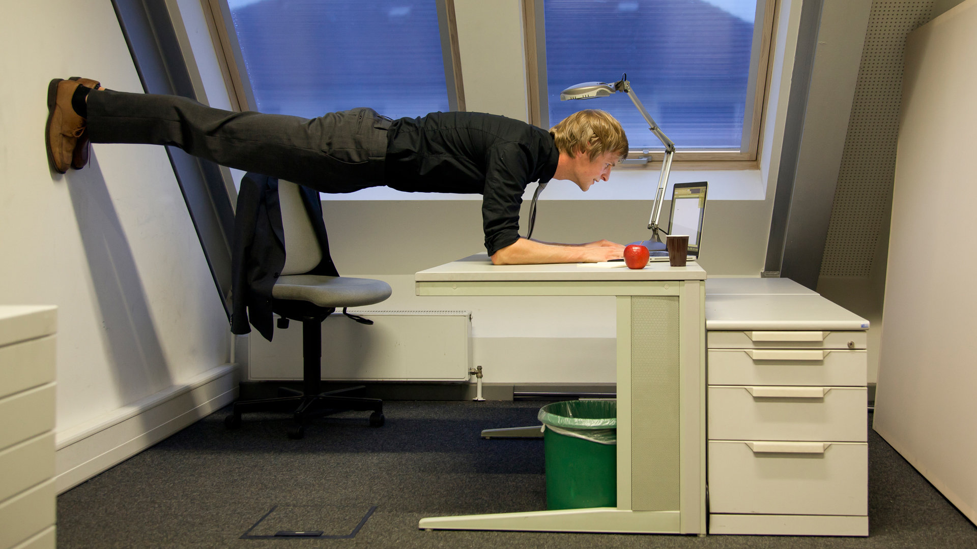 Ein Mann arbeitet in ungewöhnlicher Pose am Laptop