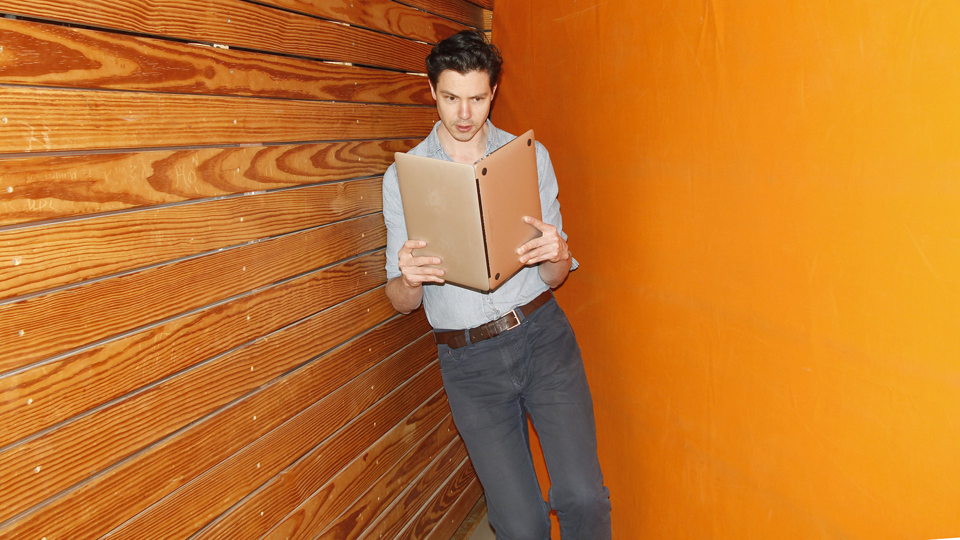 Junge Mann hält einen Laptop wie ein Buch, als würde sie darin lesen