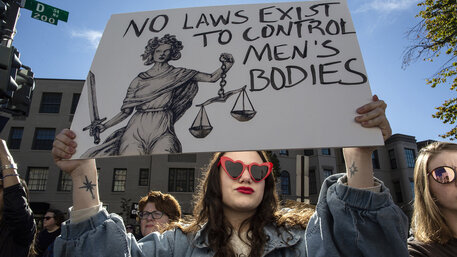 Eine Abtreibungsrechtsaktivistin mit einem Protestschild, auf dem „No Laws Exist to Control Men's Bodies“ steht,  während des Women's March vor der Heritage Foundation