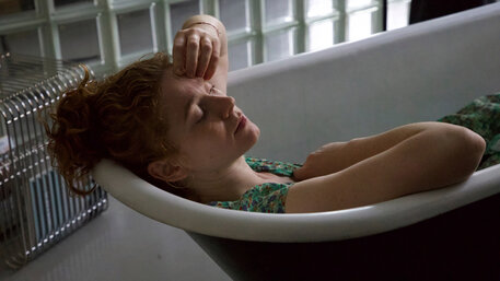 Eine junge Frau sitzt in einer leeren Badewanne