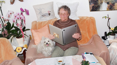 Alte Dame hält einen Laptop wie ein aufgeschlagenes Buch