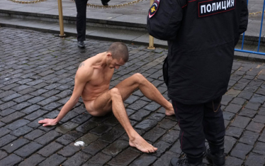 Russischer Performance-Künstler sitzt nackt auf der Straße Russischer Performance-Künstler sitzt nackt auf der Straße