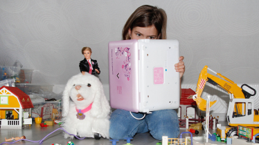 Mädchen im Kinderzimmer liest in einem Kinder-Laptop