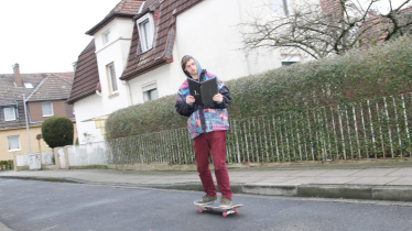 Ein Skater hält einen Laptop, als wäre es ein Buch