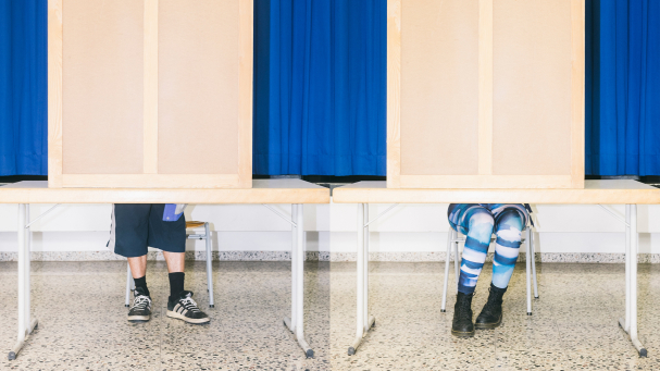 Zwei junge Menschen wählen in Wahlkabinen