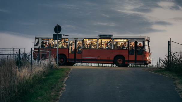 Arbeitskräfte kommen am frühen morgen mit einem alten Bus auf einer Apfelplantage in Sachsen an