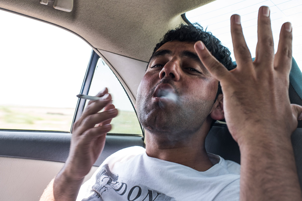 Ein rauchender Mann auf dem Rücksitz eines Autos (Foto: Chris Grodotzki)